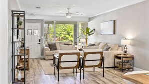 Una sala de estar con sofá, dos sillones, una mesa de centro, una estantería y una lámpara.