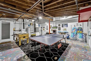Ein Zimmer mit Tischtennisplatte, Kicker und einem farbenfrohen Fußbodenmuster.