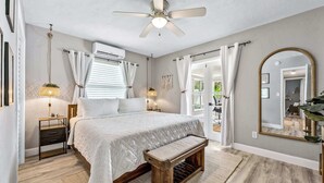Ein Schlafzimmer mit einem Bett, Nachttischen, einer Bank, einem Deckenventilator und einem großen Spiegel.