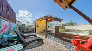 A patio area with a pergola, outdoor seating, a small kitchen area, and a colorful mural on the wall. - 1BR Studio downtown w/private rooftop outdoor soaking tub (Isla Mujeres)