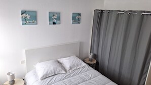 A bedroom with a bed, a bedside table with a lamp, and three wall-mounted paintings. - Apartment in the center of Guérande 4 minutes walk from the ramparts (Guérande)