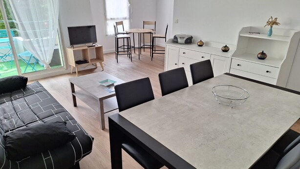 A modern living room with a sofa, a dining table, and a TV. - Apartment in the center of Guérande 4 minutes walk from the ramparts (Guérande)