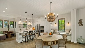 A spacious kitchen with white cabinetry, a central island, and a chandelier. - Hale Kohola by Alekona Kauai: Brand New 4BR Home w AC, close to beaches, shopping, dining (Koloa)
