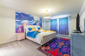 Un dormitorio con cama, mesita de noche, televisor, candelabro y ventana con cortinas.