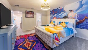 A bedroom with a large bed, a television on a dresser, and a mural on the wall. - Family-Friendly 5BR with BBQ & Resort Perks (Clermont)