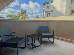 A balcony with two chairs and a small table.
