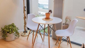 A modern room with a round table, two white chairs, a floor lamp, and a potted plant. - La Jolla Suite with Ocean View Patio (San Diego)