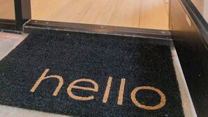 A hotel entrance with a 'hello' mat, a wooden floor, a yellow bean bag chair, and a poster on the wall. - La Jolla Suite with Ocean View Patio (San Diego)