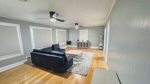 Uma sala de estar com sofá modular, mesa de centro e ventilador de teto.