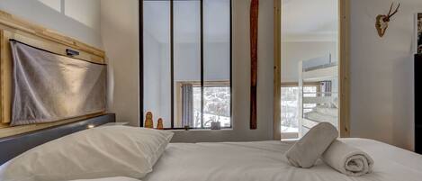 Una habitación de hotel con una cama grande, cabecera de madera, un esquí en la pared y vistas a un paisaje nevado.
