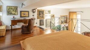 Une chambre à coucher avec un grand lit, un bureau, un fauteuil en cuir et un escalier.