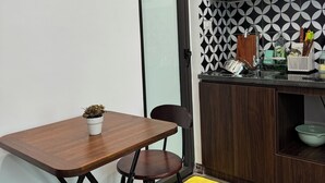 Une cuisine compacte avec une table et des tabourets en bois, une petite plante en pot et un tapis jaune sur le sol.