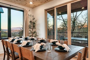 Enjoy meals in this dining area with a long table and comfortable seating, surrounded by natural views.