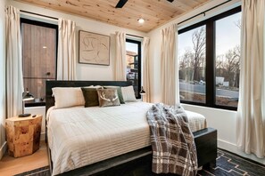 Relax in this serene bedroom with a large bed, bedside table, and a bench at the foot of the bed.