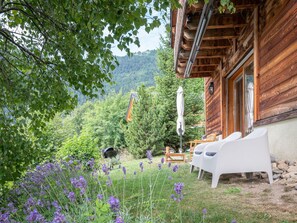 Une cabane en bois dotée d’un patio, de meubles d’extérieur et offrant une vue sur une montagne boisée.