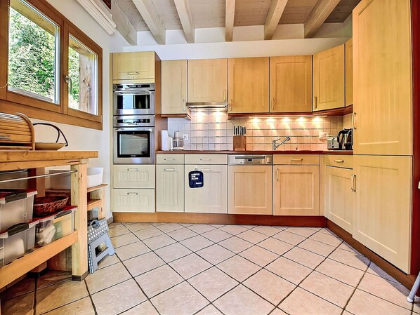Une cuisine avec des meubles en bois, des appareils électroménagers en acier inoxydable et un sol carrelé.