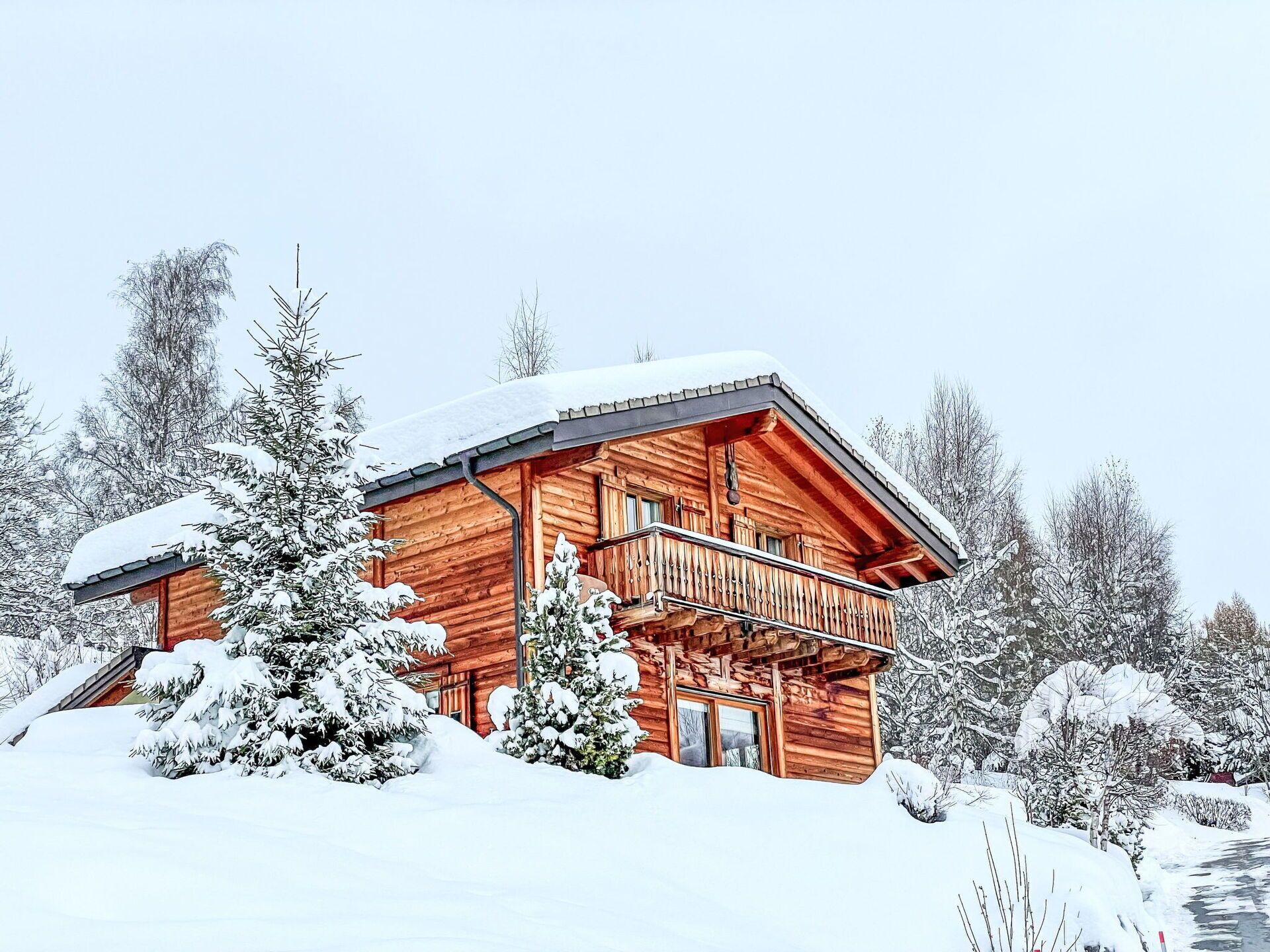 Une cabane en bois dotée d’un balcon, entourée d’arbres couverts de neige.
