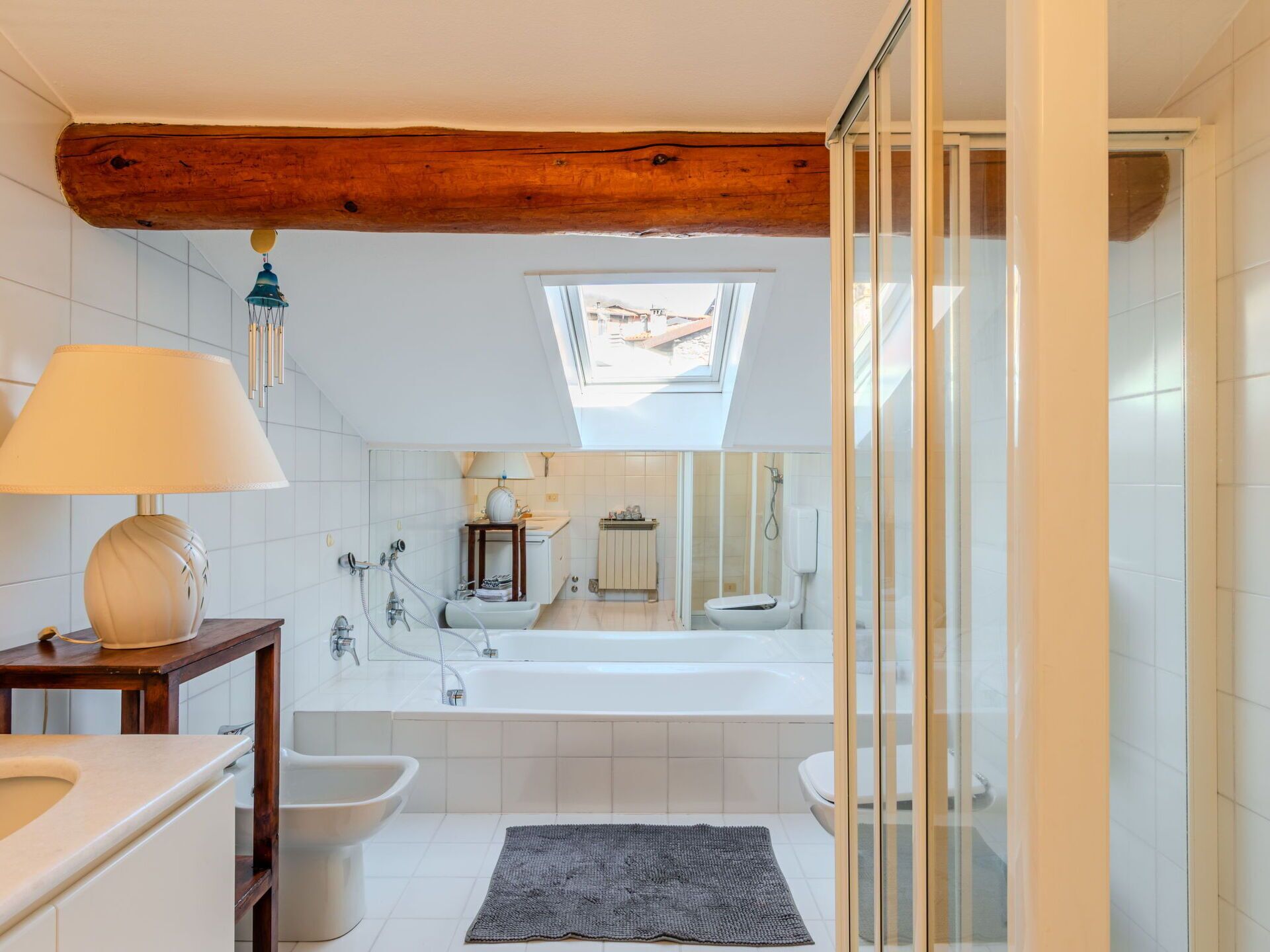 A modern bathroom with a skylight, a bathtub, a shower, and a bidet.