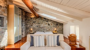 A cozy bedroom with a stone wall, wooden beams, a large bed, a sofa, and a wooden chair. - Lovely apartment for 6 people with WIFI and TV (San Siro)