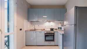Cozinha moderna com armários azul claro, geladeira de aço inoxidável, forno embutido e micro-ondas.