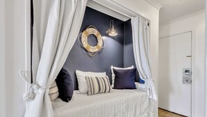 A bedroom with a bed under a canopy, a wall-mounted light fixture, and a door with a lock. - Sandy Escape - Beachside Villa! (Hilton Head Island)