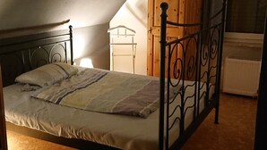 Un lit simple dans une chambre avec un plafond en pente, une armoire en bois et un radiateur.