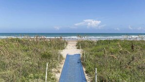 A beach path leading to the ocean with a clear sky.