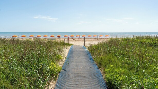 Un sentier qui longe la plage et mène aux parasols.