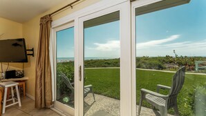 Une pièce dotée d’une porte-fenêtre coulissante donnant sur un balcon avec vue sur la plage.