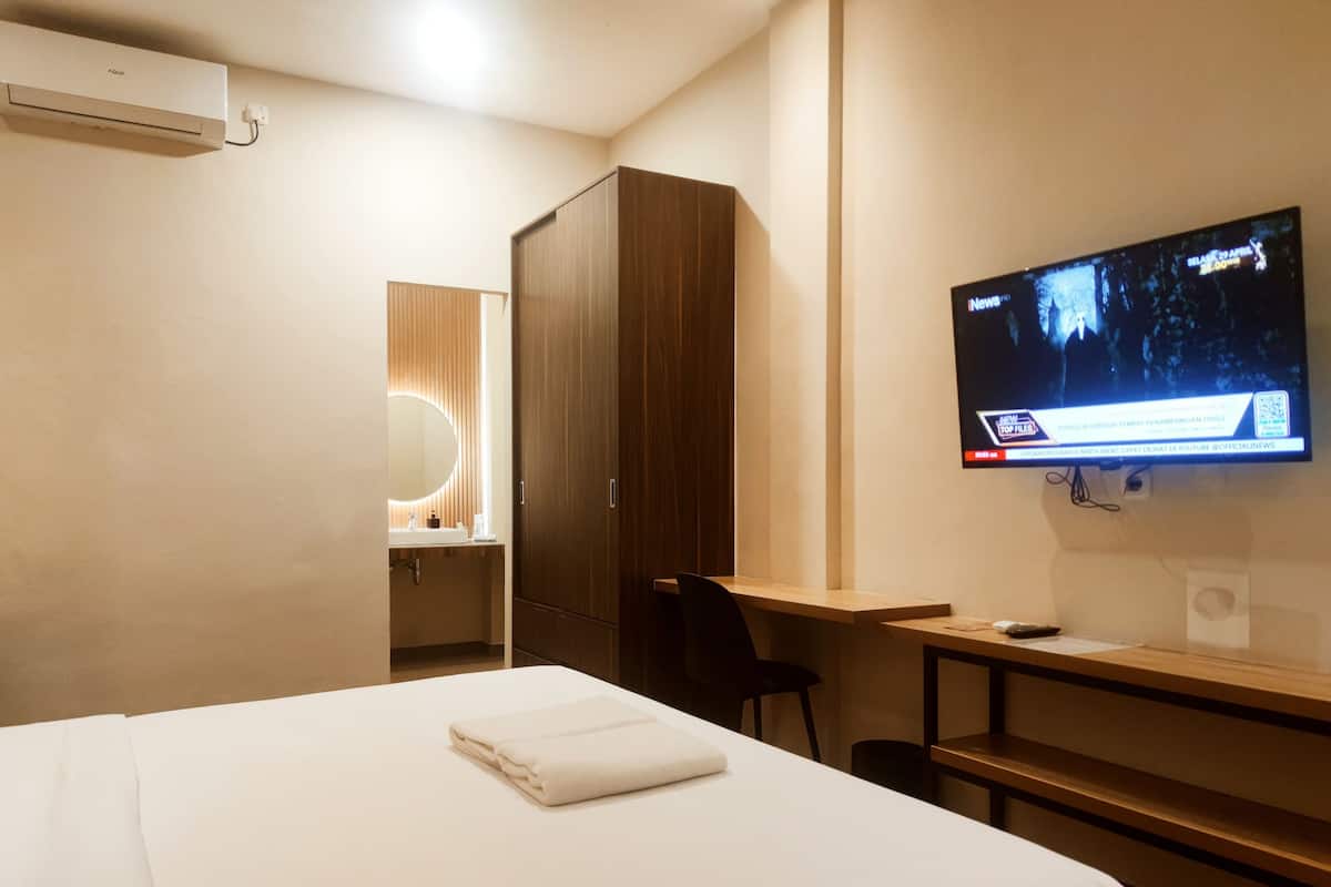 Een hotelkamer met een bed, een bureau, een televisie en een kledingkast.