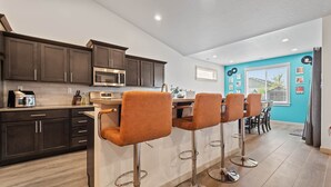 A modern kitchen with dark cabinets, stainless steel appliances, and a bar area with four stools. - A Motown-Inspired Vinyl Retreat (Meridian)