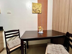 A dining table with two chairs, a vase with flowers, and a wall-mounted picture of Paris.