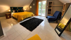 Un dormitorio con una cama, una silla, un tapete negro, un espejo y una ventana con cortinas.