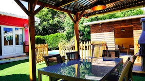Un patio exterior con una mesa y sillas de vidrio, rodeado de vallas de madera y una piscina.