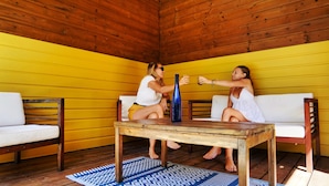 Dos personas sentadas en sofás blancos en una habitación de madera con paredes amarillas.
