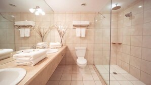 Een moderne badkamer met een douchecabine van glas, een toilet en een wastafel met gestapelde handdoeken.