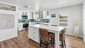 Una cocina moderna con armarios blancos, una isla blanca y un salpicadero con azulejos azules.
