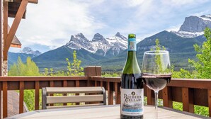 A bottle of Riesling wine and a glass on a table with a mountain view.