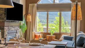 A dining area with a table set for four, a sofa, and a television mounted on the wall.