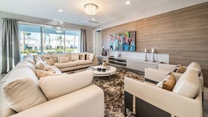 Un salon moderne avec un grand canapé, une table basse et un téléviseur fixé au mur.