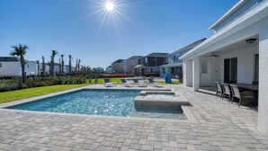 Une piscine avec des chaises longues, un espace patio et une vue sur des immeubles d’habitation.