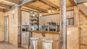 Una cocina rústica con paredes de madera, una barra y dos taburetes.
