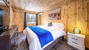 Camera da letto con pannelli in legno, un letto, un comodino e un quadro appeso al muro.