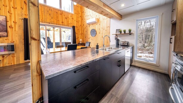 Una cucina moderna con pareti in legno, una grande isola e vista sull'esterno.