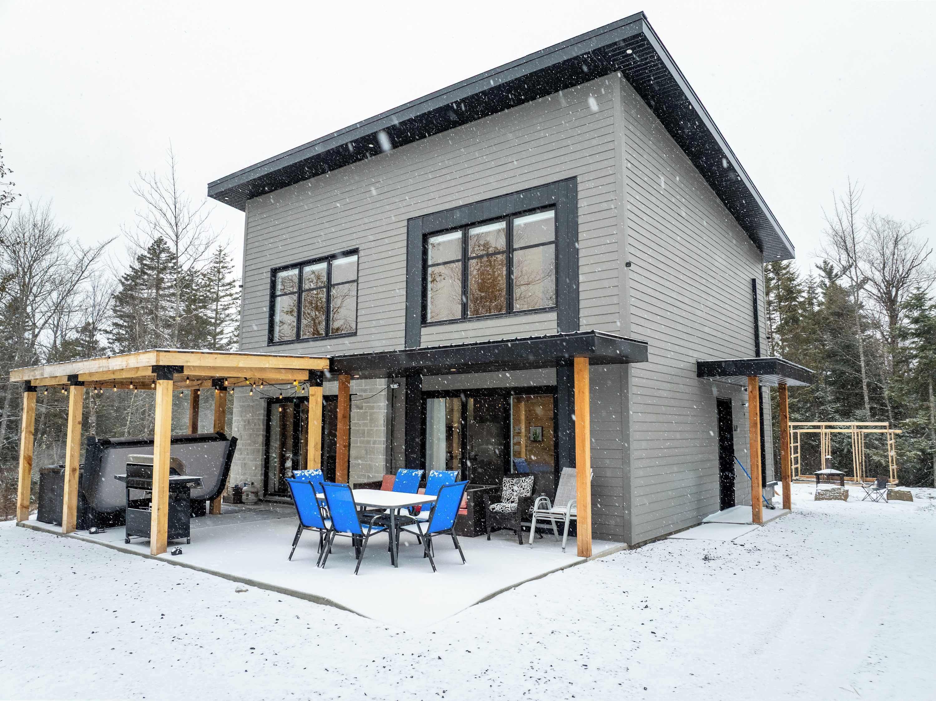 Una casa a due piani con un patio coperto, un barbecue e mobili da esterno.