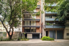 Ein mehrstöckiges Wohngebäude mit Balkonen, einer Garage und einem Baum im Vordergrund.