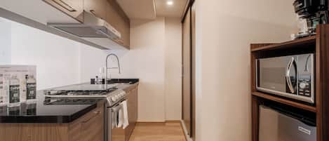 A modern kitchen with a stove, oven, microwave, and a coffee maker.