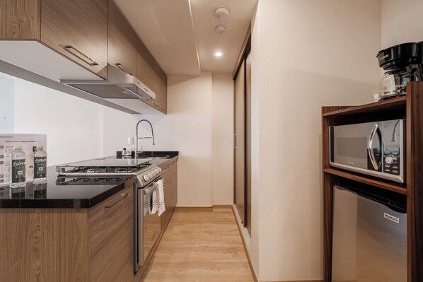 A modern kitchen with a stove, oven, microwave, and a coffee maker.