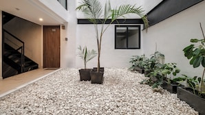 Un bâtiment moderne doté d’un escalier, d’une porte portant l’inscription « 100 » et de plantes en pot disposées sur un sol recouvert de gravier.