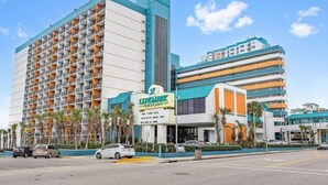 Un hotel de varios pisos con un llamativo letrero 'Landmark', que presenta un diseño moderno con balcones y un estacionamiento al frente.